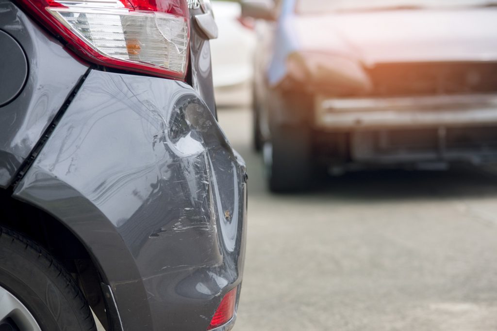 close up of back bumper of a gray car with a dent